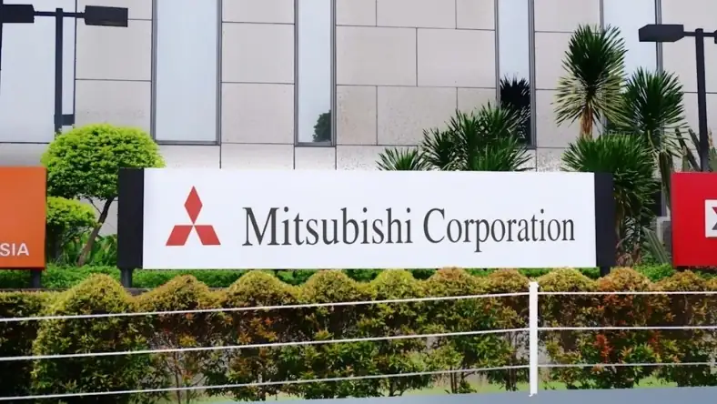Mitsubishi Corporation logo on a freestanding sign outside a corporate office with palm trees and hedging