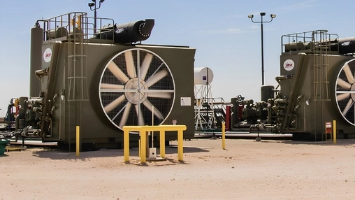 Side angle view of a gas compression unit with its circular fan exhaust silencer and connected pipework