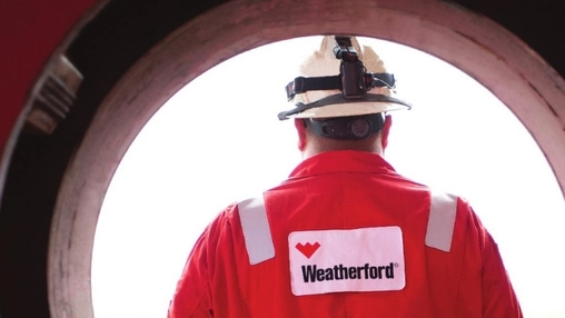 Worker wearing red branded coveralls and safety helmet seen from behind through a circular pipe frame
