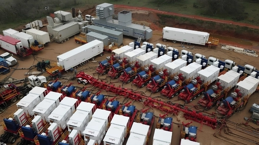 Aerial view of a hydraulic fracturing site with pumping units and support trailers