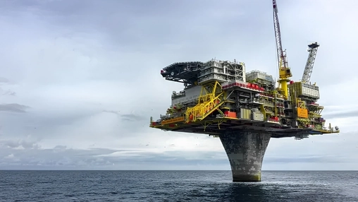 An offshore oil platform operating above calm waters under a cloudy sky