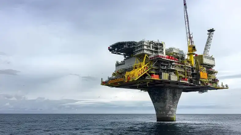 An offshore oil platform operating above calm waters under a cloudy sky