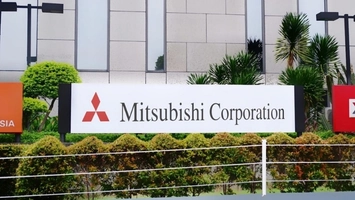 Mitsubishi Corporation logo on a freestanding sign outside a corporate office with palm trees and hedging